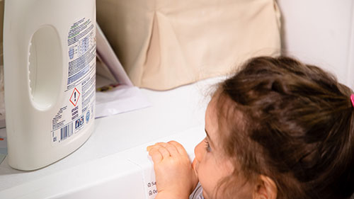 a young child looks at a bottle with a pictogramme