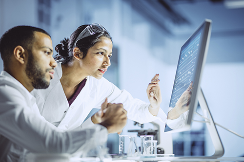 male and female scientist in front of a screen