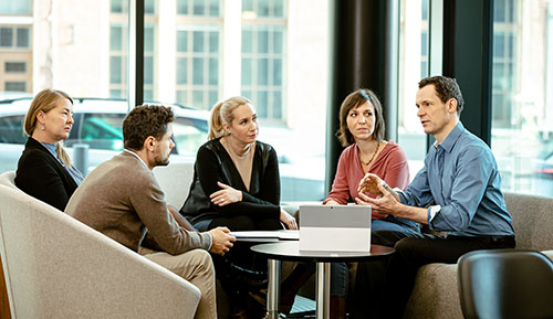 five people sitting around a table discussing